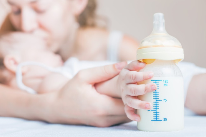 baby reaching for bottle of breastmilk