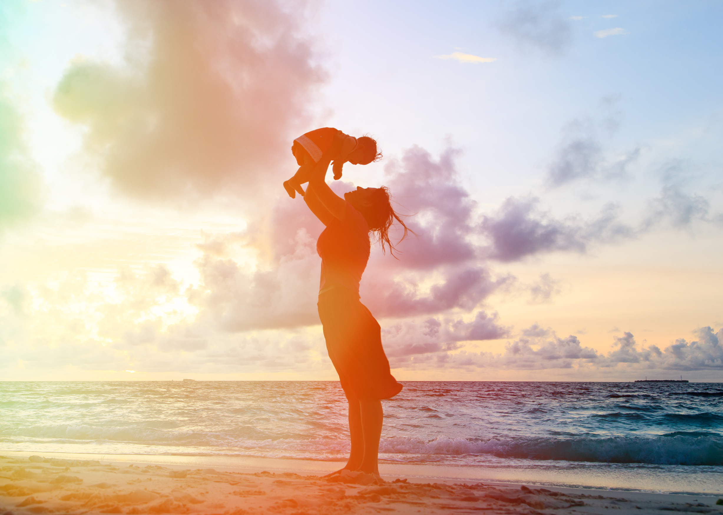 mother and baby having fun at sunset beach
